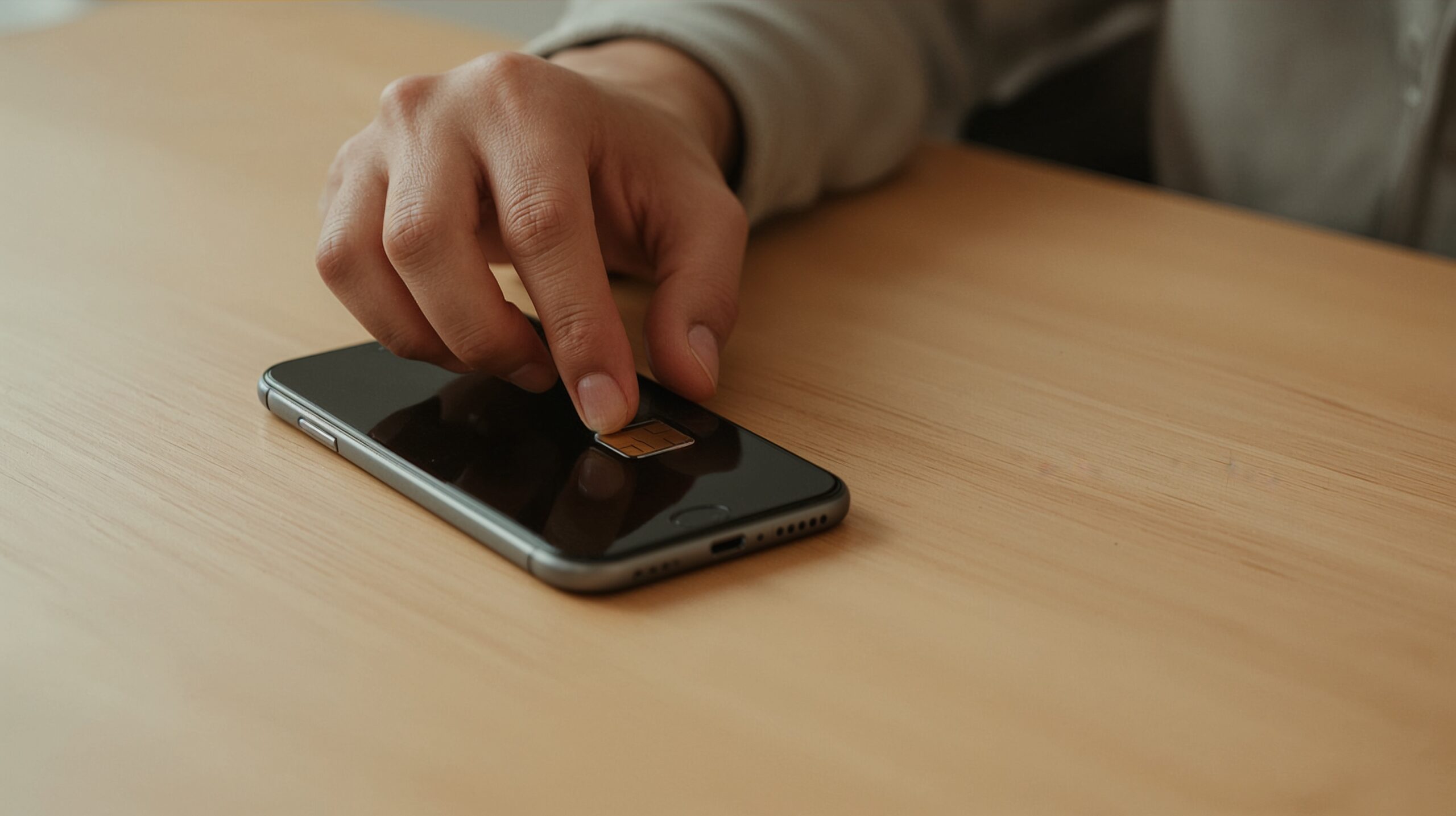 A hand placing a SIM card into a smartphone